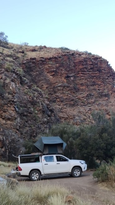 camping car with pitched roof tent in front of cliff