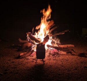camp fire at night with cast iron kettle in coals