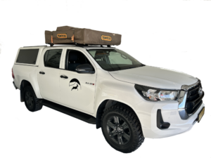 White automatic 4x4 pickup doublecabin with one standard softshell rooftop tent on top and camping for two people