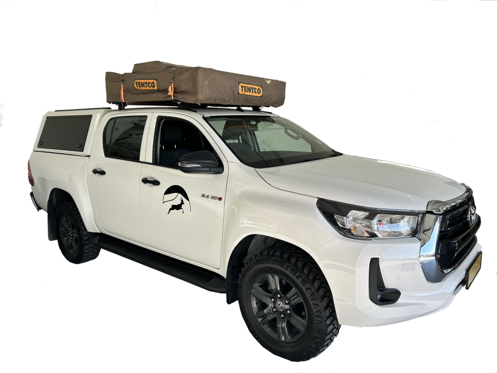 White automatic 4x4 pickup doublecabin with one standard softshell rooftop tent on top and camping for two people