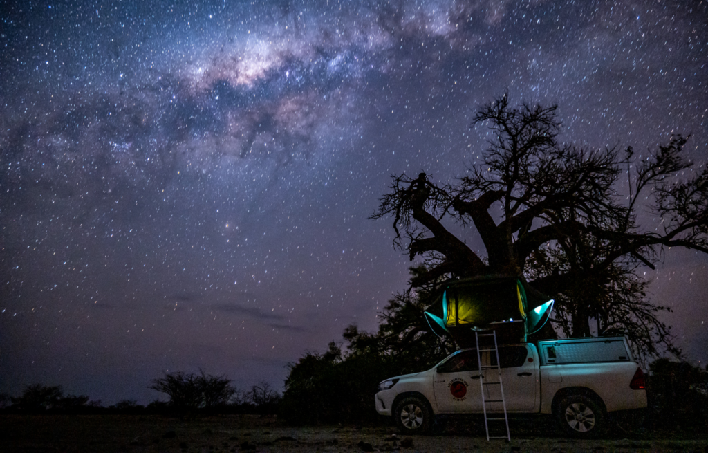 Camping car with rooftop tent under milky way