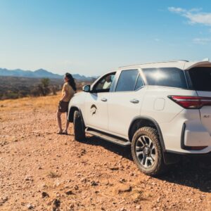 Women enjoying view over Namibian landscape leaning against Toyota Fortuner SUV 4x4