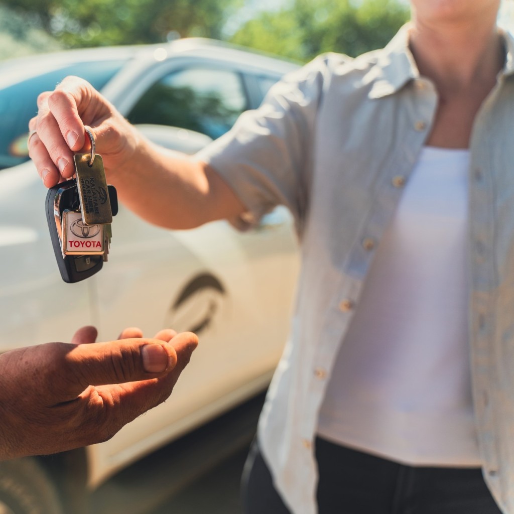 Person handing over keys to rental vehicle to another person