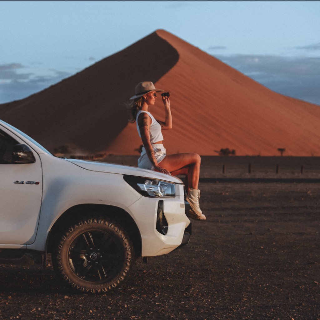 Woman sitting on 4x4 vehicle in Namibia with binoculars